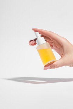 Cropped hand holding yellow serum cosmetic bottle