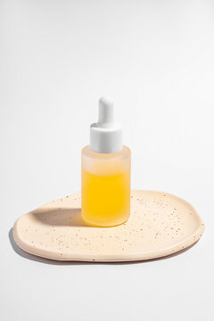 Elegant cosmetics serum bottle on a ceramic tray