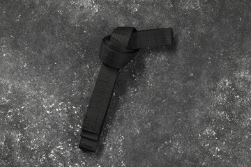 Black karate belt on gray textured background, top view © New Africa