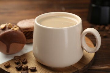 Cup of coffee and delicious macarons on wooden table, closeup