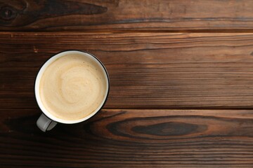 Tasty cappuccino in cup on wooden table, top view. Space for text
