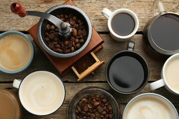 Different coffee drinks in cups, beans and manual grinder on wooden table, flat lay