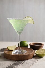 Delicious Margarita cocktail in glass, salt and limes on table