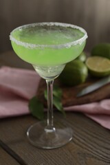 Delicious Margarita cocktail in glass on wooden table, closeup