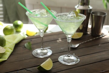 Delicious Margarita cocktail in glasses and lime on wooden table, closeup