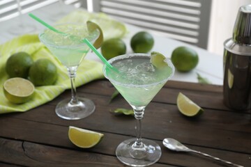 Delicious Margarita cocktail in glasses and lime on wooden table, closeup
