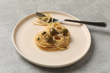 Heart made of tasty spaghetti, olives, cheese and fork on light grey table