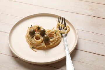 Heart made of tasty spaghetti, fork, olives and cheese on light wooden table. Space for text