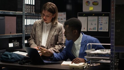 African american and caucasian police officers conduct extensive investigations and analyse...