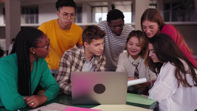 Group of diverse multiethnic smiling young students using laptop studying gathering in classroom. Academics multiracial people classmates working in a project creative inside of university building