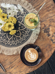 A cup of coffee with latte art on top on wooden table with  mango smoothie
