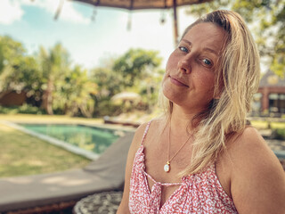 Portrait of a beautiful middle-aged blonde woman with a frangipani flower