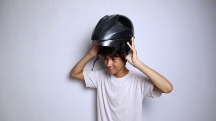 young Asian man in white shirt gesturing using a helmet
