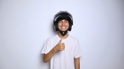 Excited young Asian man in white shirt gesturing with a helmet and thumbs up