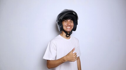 Excited young Asian man in white shirt gesturing with a helmet and thumbs up