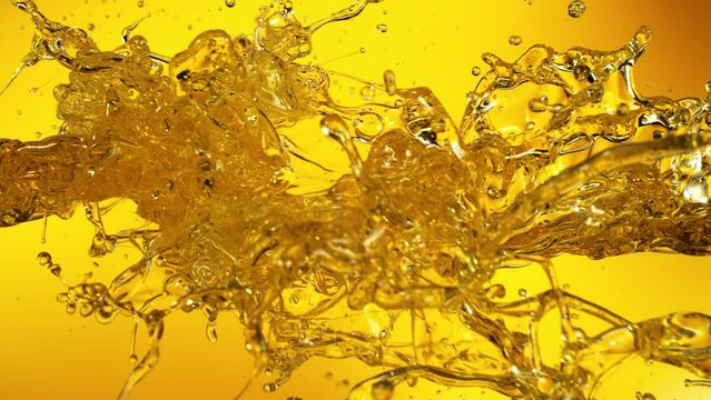 Super Slow Motion Shot of Oil Splashes Flying Towards on Golden Background at 1000fps.