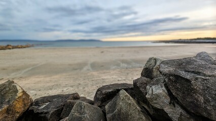 Costal landscape, focus on rocks in foreground, blurred background, sunset beach scenery, nature