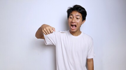 Excited young Asian man in white shirt gestures while eating holding a spoon made of bamboo