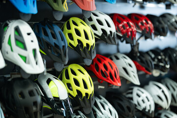 Variety of bicycle helmets in different colors and designs neatly displayed on shelves in...
