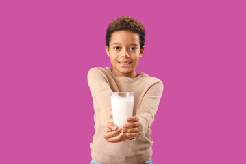 Little African-American boy with glass of milk on purple background