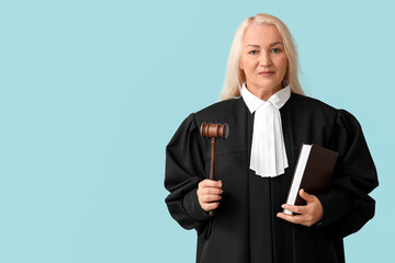 Mature female judge with book and gavel on blue background