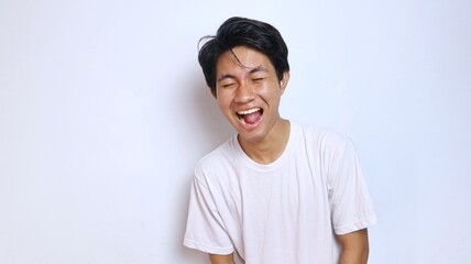 young asian man in white shirt funny expression laughing, happy