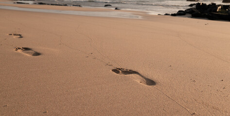 The beach is empty and the sand is dry. The only footprints are from people walking on the beach