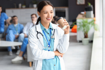 Female Asian doctor with coffee cup in hospital rest room