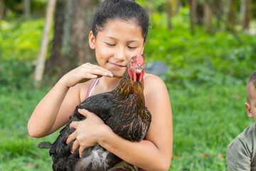 latina brunette girl holding a black hen in her hands while caressing and treating it with love