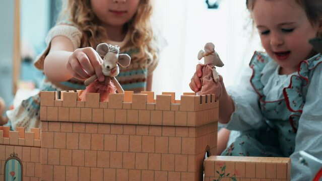 Two little girls play together with a cardboard castle