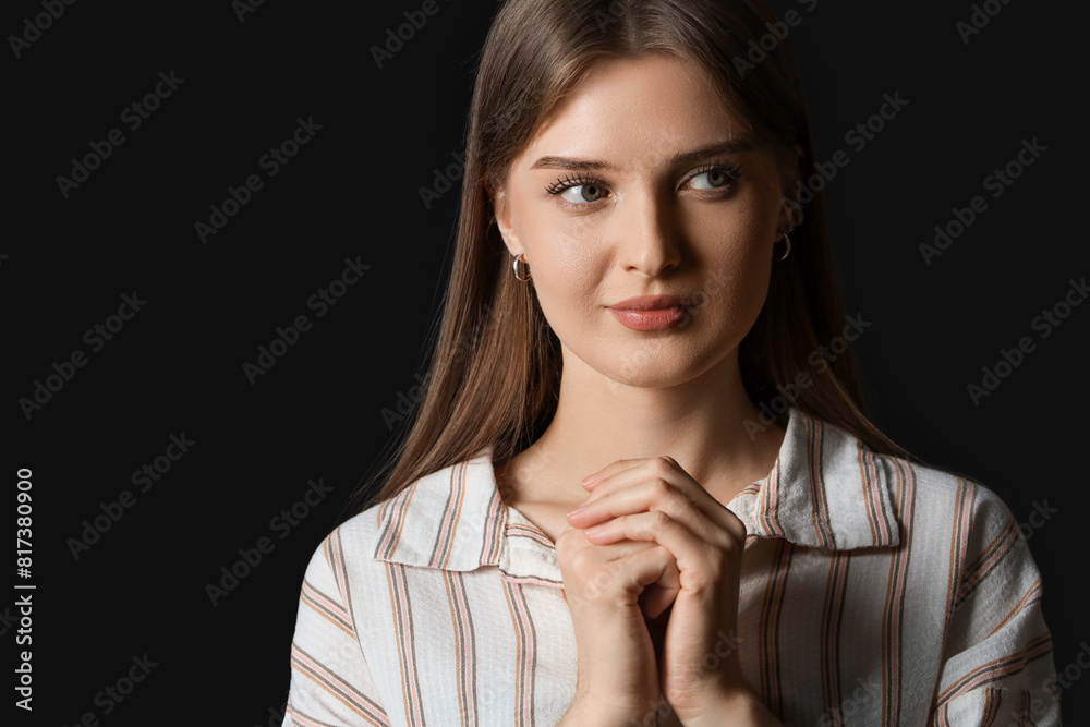 Wall mural young woman praying on black background, closeup