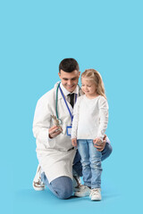 Male pediatrician with toy and little girl on blue background