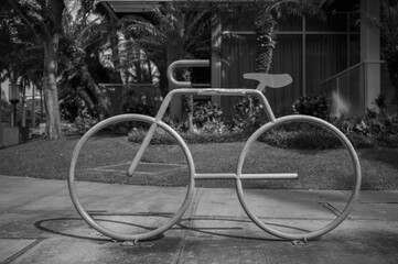 Metal Bicycle Stand on a Sidewalk with grass and plants in the Background.