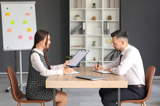 Human resources manager interviewing applicant at table in office