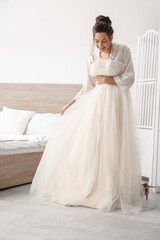Naklejka premium Young bride with her wedding dress in bedroom