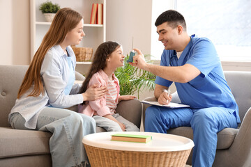 Little girl with her mother and doctor using inhaler at home