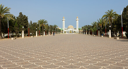 Fototapeta na wymiar Scenic general view of sun-drenched Mausoleum of Habib Bourguiba in Tunisian city of Monastir, showcasing exquisite Islamic architecture with golden dome and twin white minarets