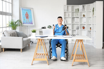 Young male doctor in wheelchair with sphygmomanometer working at his workspace in clinic