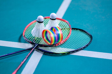 Rainbow wristbands, used cream white badminton shuttlecock and racket placed on floor in indoor...