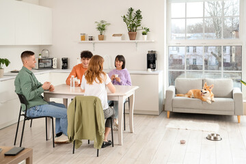Young colleagues with Corgi dog having coffee break in kitchen
