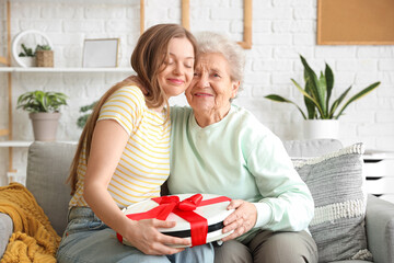 Young woman gifting robot vacuum cleaner to her grandmother at home