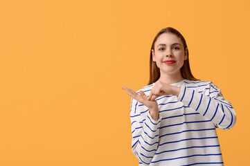 Young deaf mute woman using sign language on orange background