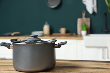 Wooden counter with cooking pot in interior of modern kitchen, closeup