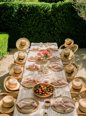 A long outdoor dining table  set up in the middle of a grassy yard with tall hedges.Minimal creative party and nature concept