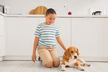 Little African-American boy with cute beagle dog sitting on floor at home
