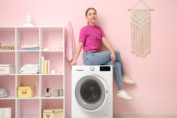 Young woman sitting on washing machine in laundry room