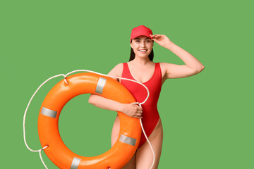Female lifeguard with ring buoy on green background