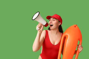 Female lifeguard with rescue buoy and megaphone on green background