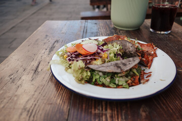 A delicious plate featuring two tacos and a side of fresh salad. The tacos are filled with savory...