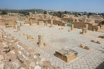 Obraz premium Partially reconstructed Roman Baths complex in ancient settlement of Sbeitla in Tunisia with well preserved mosaic floor and remnants of stone columns on sunny day